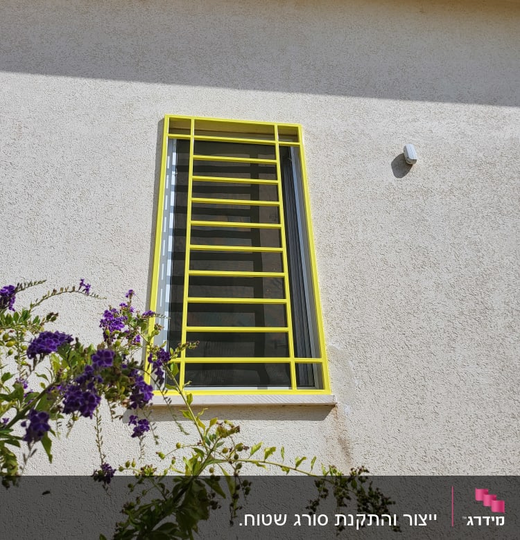 חלון עם סורגים צהובים על קיר בהיר